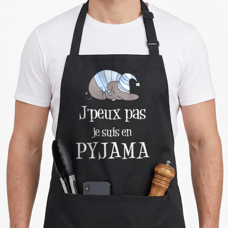 Tablier de cuisine noir avec un éléphant dormant en pyjama et le texte J'peux pas je suis en pyjama imprimé en blanc.