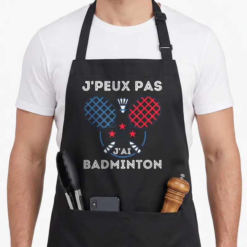 Tablier de cuisine noir avec deux raquettes de badminton croisées et le texte j'peux pas j'ai badminton en blanc.