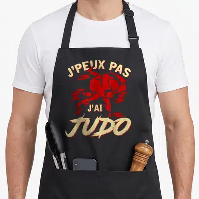 Tablier de cuisine noir avec inscription j'peux pas j'ai Judo et silhouettes rouges de judokas en mouvement.
