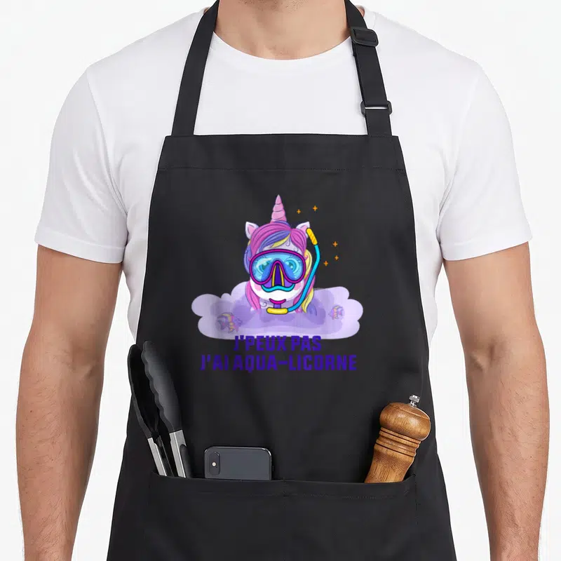 Tablier de cuisine noir avec une licorne en masque de plongée et le texte j'peux pas j'ai aqua-licorne imprimé en violet.