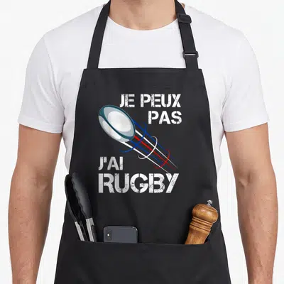 Tablier de cuisine noir avec motif ballon de rugby et texte je peux pas j'ai rugby en blanc