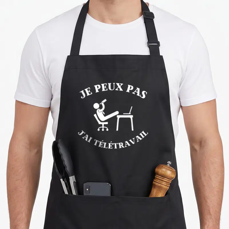 Tablier de cuisine noir avec illustration blanche d'une personne allongée sur un fauteuil devant un ordinateur portable.