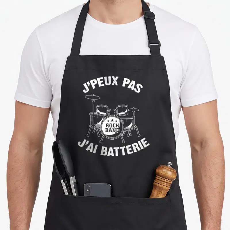 Tablier de cuisine noir avec illustration blanche d'une batterie et le texte J'peux pas j'ai batterie.