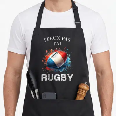 Tablier de cuisine noir avec ballon de rugby aux couleurs du drapeau français et texte humoristique blanc.