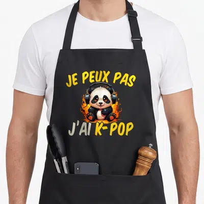 Tablier de cuisine noir avec un panda muni d'écouteurs et le texte Je peux pas j'ai K-Pop sur fond de flammes jaunes.