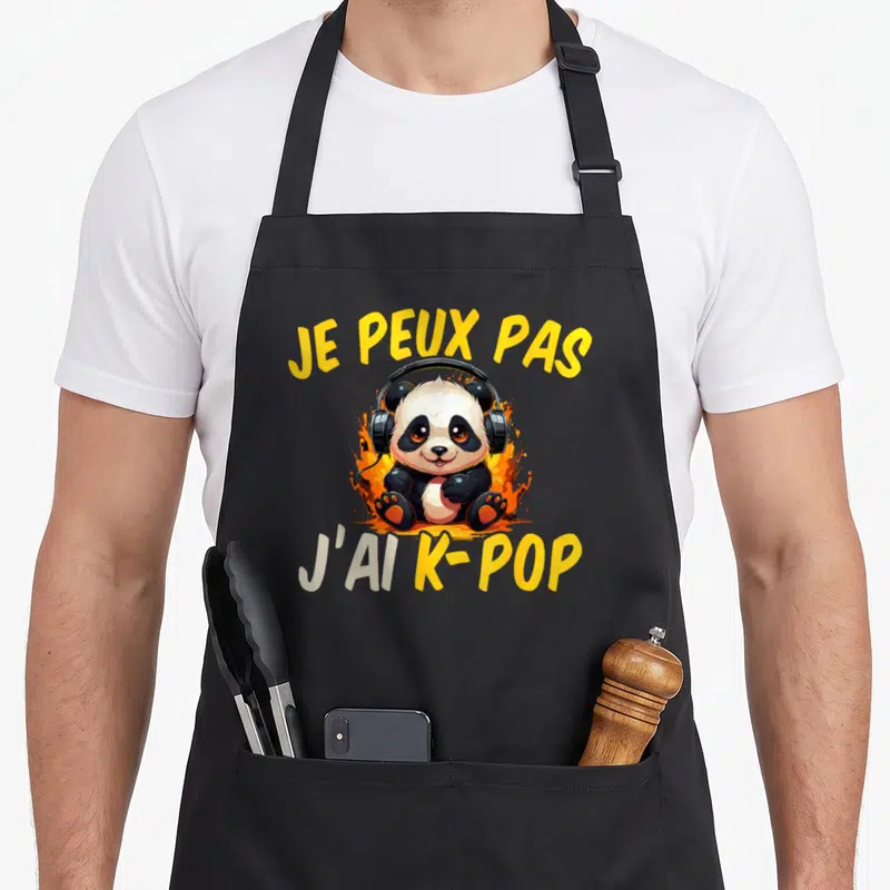 Tablier de cuisine noir avec un panda muni d'écouteurs et le texte Je peux pas j'ai K-Pop sur fond de flammes jaunes.