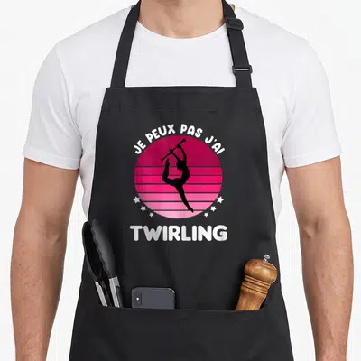 Tablier de cuisine noir avec motif rose rétro, silhouette de twirling bâton et texte blanc Je peux pas j'ai.