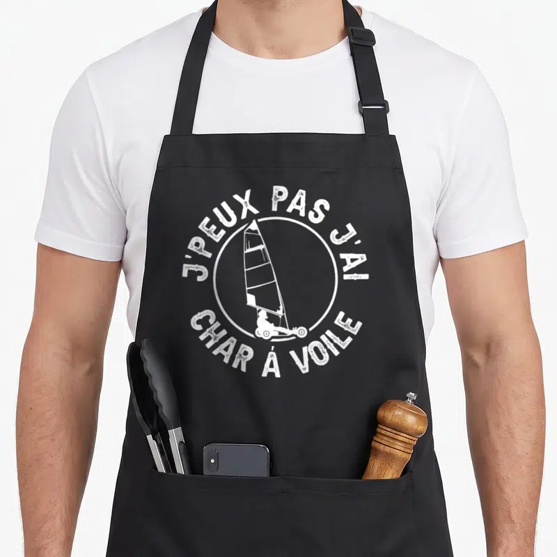 Tablier de cuisine noir avec inscription blanche j'peux pas j'ai char à voile et dessin de voile sur roulettes.