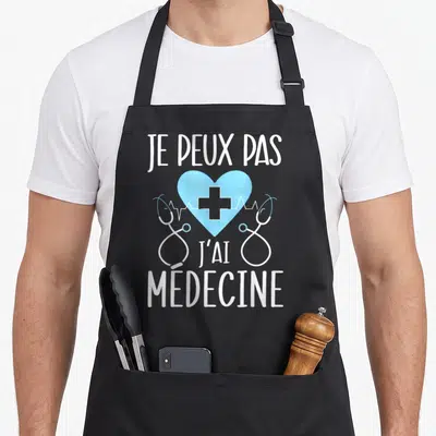 Tablier de cuisine noir avec inscription je peux pas j'ai médecine et stéthoscope autour d'un cœur bleu.