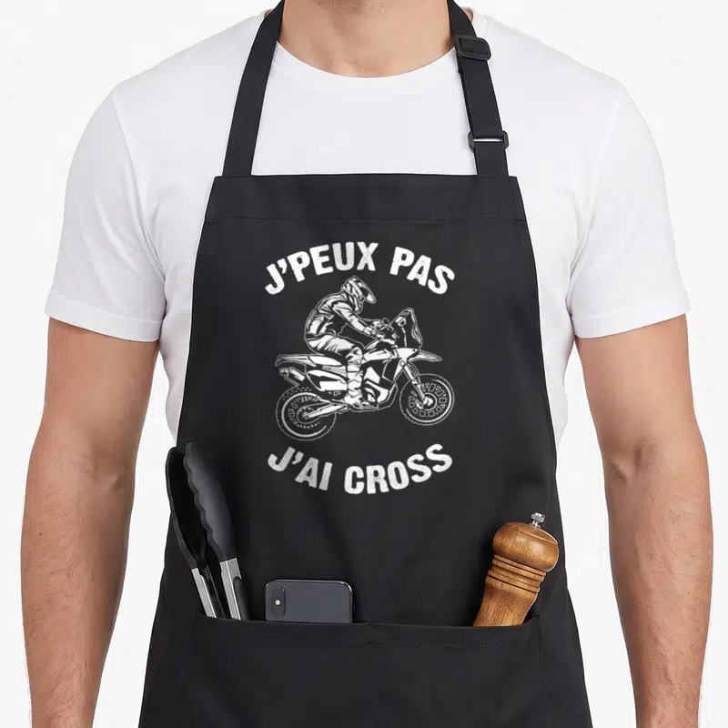 Tablier de cuisine noir avec illustration blanche d'un pilote de moto cross et le texte j'peux pas j'ai cross.