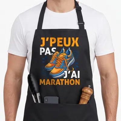 Tablier de cuisine noir avec illustration de chaussures de course orange et bleue et texte humoristique sur le fond.