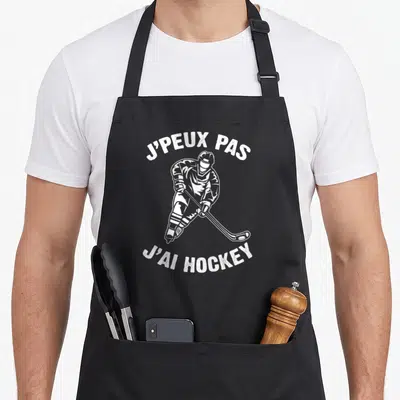 Tablier de cuisine noir avec illustration blanche d'un joueur de hockey sur glace tenant sa crosse et un disque.