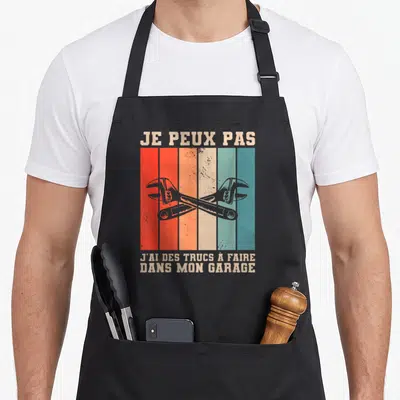 Tablier de cuisine noir avec inscription je peux pas et deux clés anglaises croisées sur bandes colorées vintage.