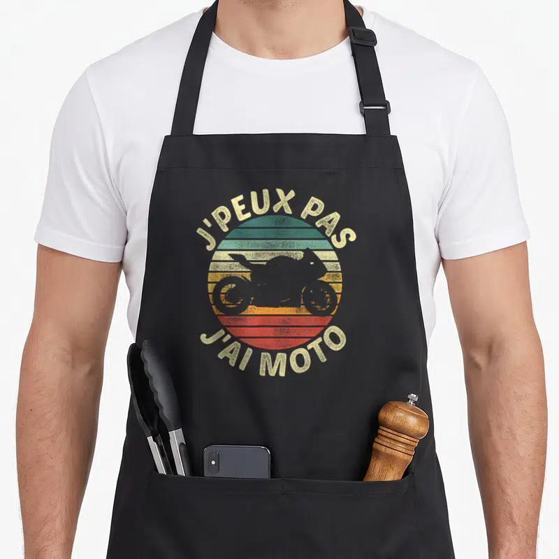 Tablier de cuisine noir avec motif circulaire retro et silhouette de moto grise au centre.