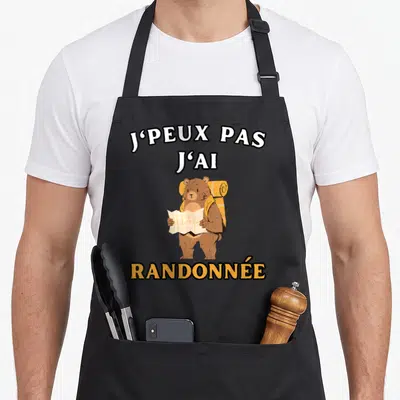 Tablier de cuisine noir avec ours portant sac à dos et carte illustrant la phrase j'peux pas j'ai randonnée.