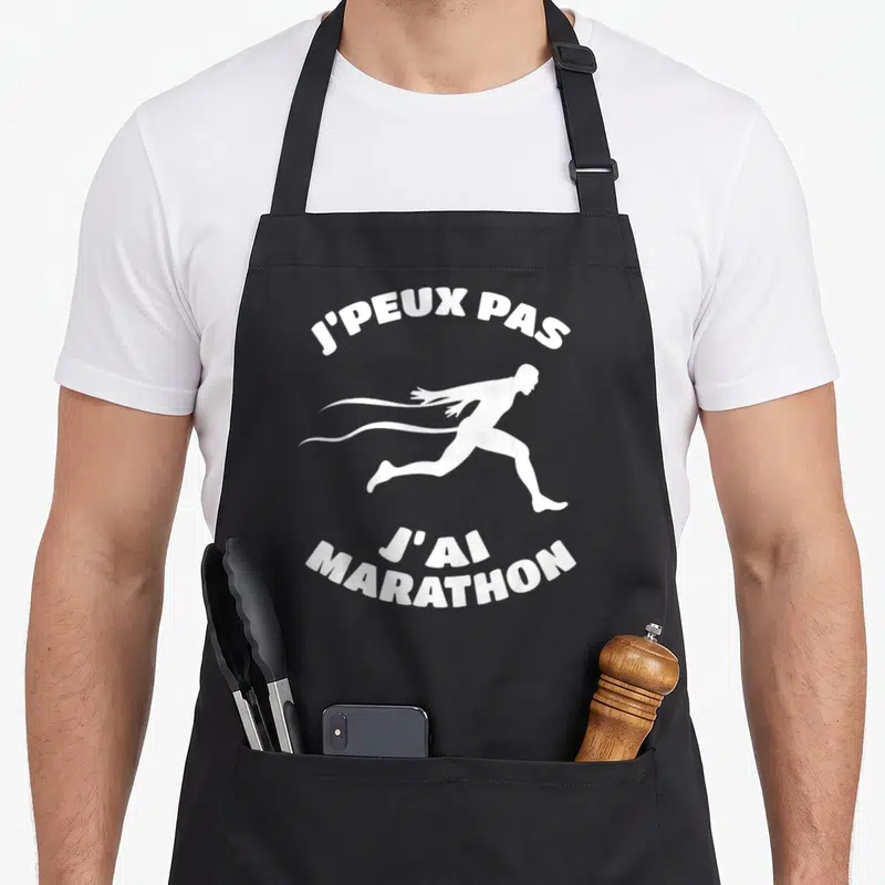 Tablier de cuisine noir avec silhouette de coureur blanc et texte j'peux pas j'ai marathon imprimé en haut et en bas.