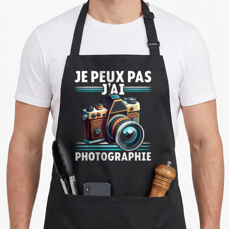 Tablier de cuisine noir avec illustration d'un appareil photo vintage et le texte je peux pas j'ai photographie en blanc.