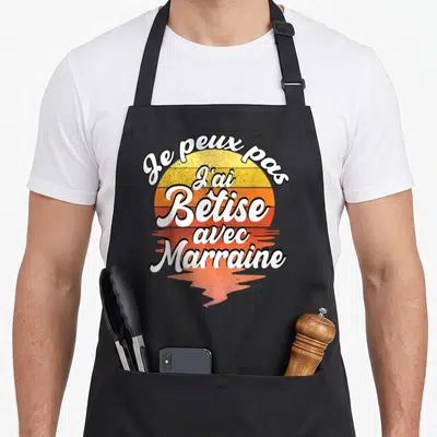 Tablier de cuisine noir avec motif texte blanc Je peux pas j'ai bêtise avec marraine sur fond de soleil orange