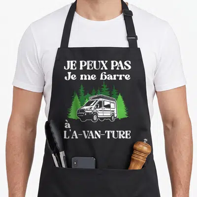 Tablier de cuisine noir avec illustration d'un van blanc devant des arbres verts et un texte humoristique en blanc.