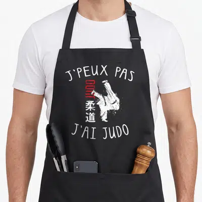 Tablier de cuisine noir avec inscription JPEUX PAS JAI JUDO et silhouette de judoka blanche.