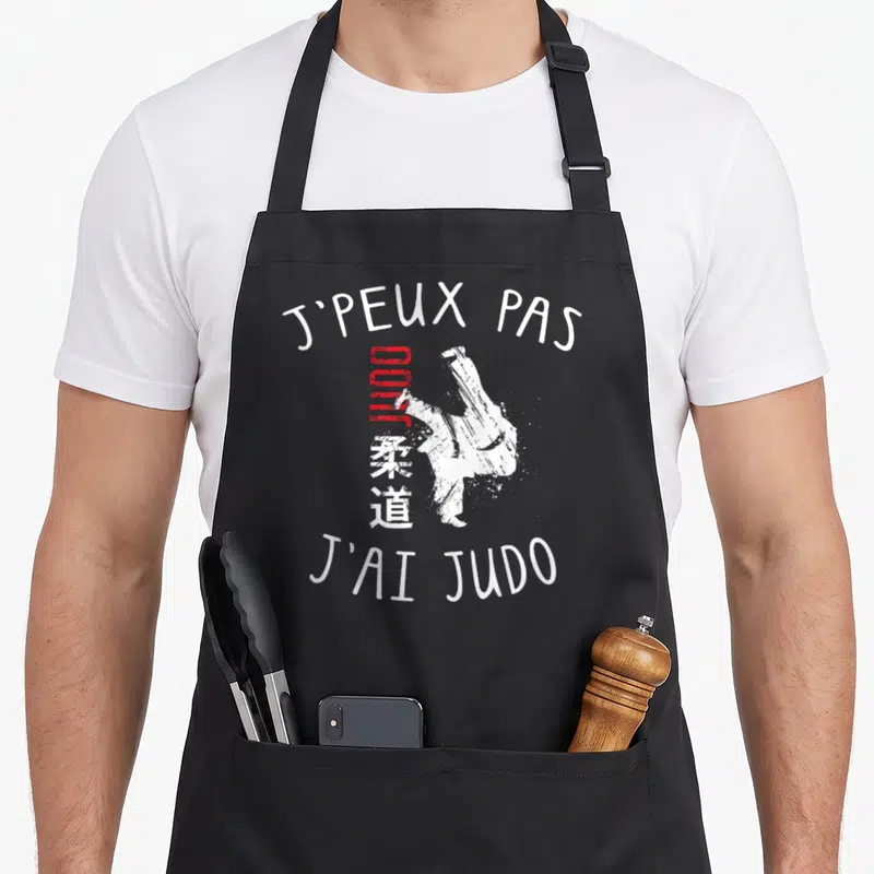 Tablier de cuisine noir avec inscription JPEUX PAS JAI JUDO et silhouette de judoka blanche.