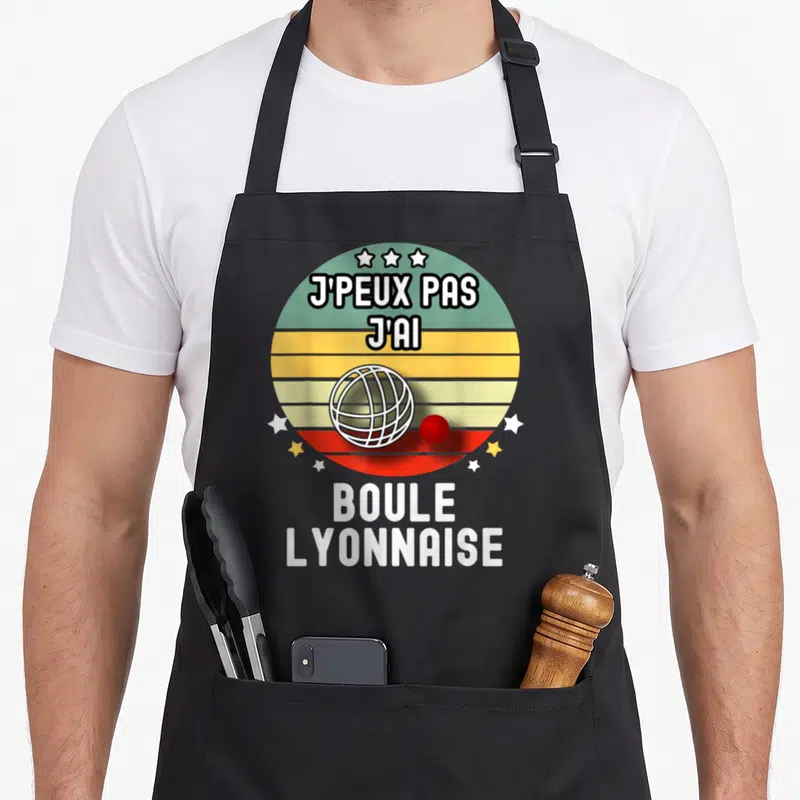 Tablier de cuisine noir avec motif circulaire rétro affichant une boule et une balle rouge sous le texte j'peux pas j'ai boule lyonnaise.