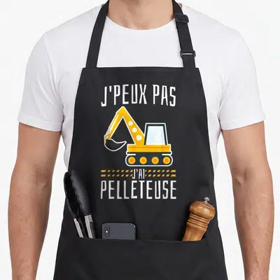Tablier de cuisine noir avec illustration excavatrice jaune et texte j'ai pelleteuse en blanc.