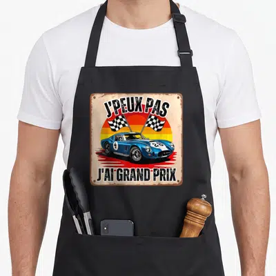 Tablier de cuisine noir avec illustration rétro d'une voiture de course bleue et drapeaux à damier sous le texte j'peux pas j'ai grand course