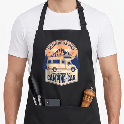 Tablier de cuisine noir avec illustration vintage d'un camping-car orange devant des montagnes bleues et des pins.