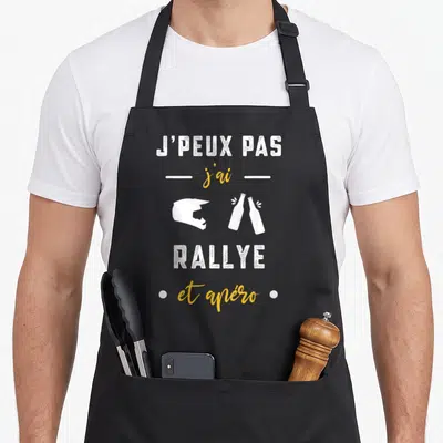 Tablier de cuisine noir avec inscription j'peux pas j'ai rallye et apéro illustré d'un casque et deux bouteilles.
