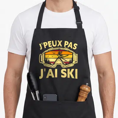 Tablier de cuisine noir avec inscription j'peux pas j'ai ski et illustration de lunettes de ski vintage.