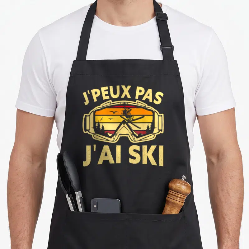 Tablier de cuisine noir avec inscription j'peux pas j'ai ski et illustration de lunettes de ski vintage.