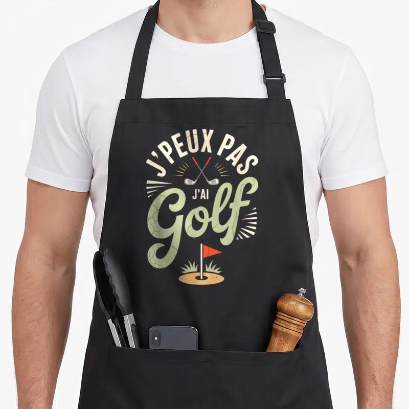 Tablier de cuisine noir avec inscription j'peux pas j'ai golf et illustration de clubs de golf croisés au-dessus d'un trou.