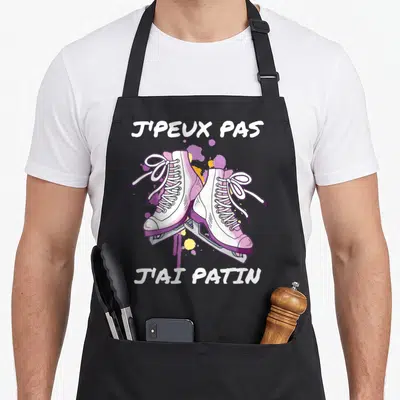 Tablier de cuisine noir avec illustration de patins à glace roses et texte blanc humoristique.