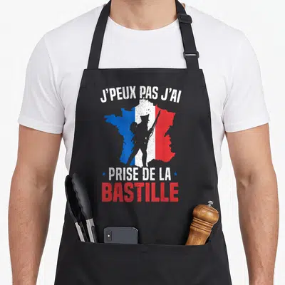 Tablier de cuisine noir avec silhouette de révolutionnaire sur carte de France tricolore et texte J'peux pas j'ai prise de la Bastille.