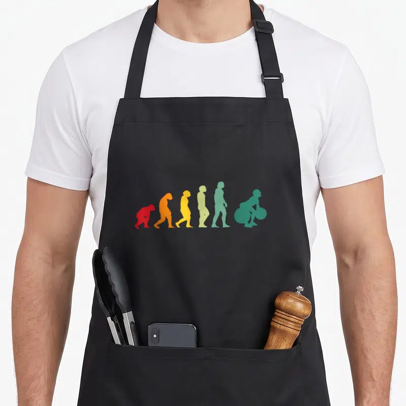 Tablier de cuisine noir avec silhouette évolutive colorée se transformant en personne soulevant une barre.