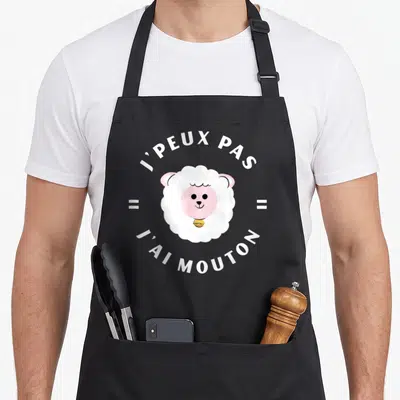 Tablier de cuisine noir avec tête de mouton rose et texte blanc j'peux pas j'ai mouton