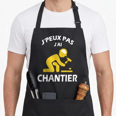 Tablier de cuisine noir avec illustration jaune d'un ouvrier au travail et texte blanc J'peux pas j'ai Chantier.