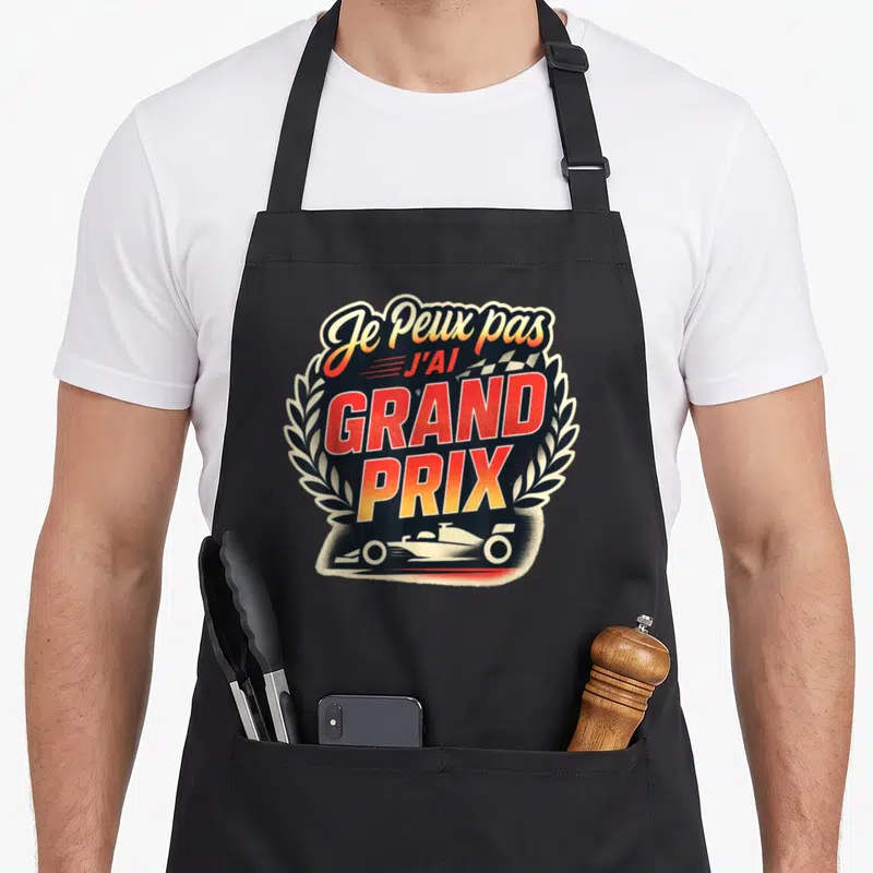Tablier de cuisine noir avec illustration de voiture de course et texte Je Peux pas J'ai Grand « Prix » encadré par des lauriers.