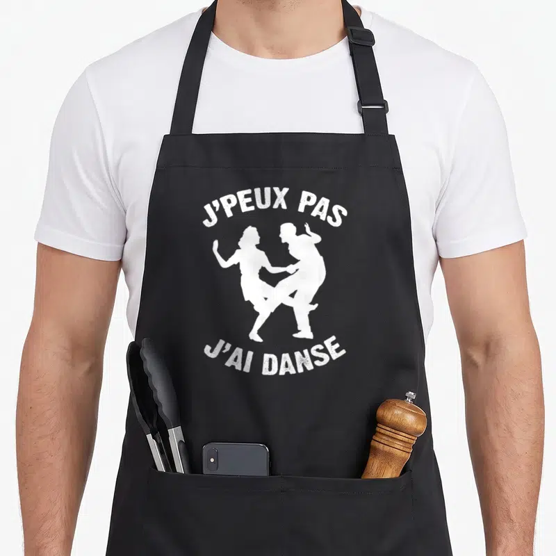 Tablier de cuisine noir avec texte blanc et silhouettes d'un couple en train de danser ensemble.
