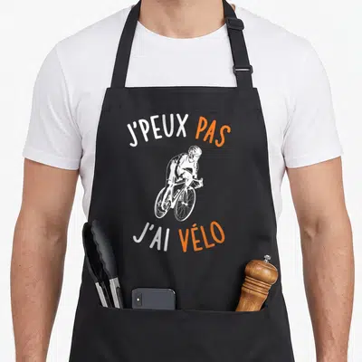 Tablier de cuisine noir avec illustration d'un cycliste et le texte J'peux pas j'ai vélo en blanc et orange.