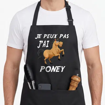 Tablier de cuisine noir avec illustration d'un poney souriant et le texte je peux pas j'ai poney en blanc.