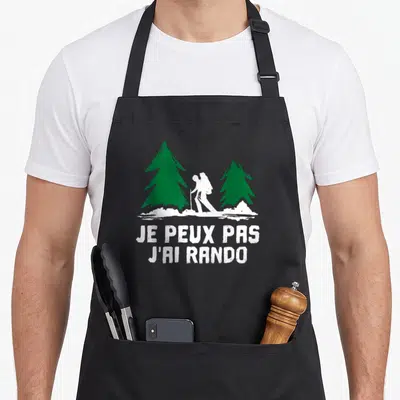 Tablier de cuisine noir avec silhouette de randonneur entre deux pins verts et texte blanc Je peux pas j'ai rando.