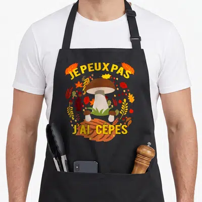 Tablier de cuisine noir avec illustration colorée d'un grand cèpe entouré de feuilles d'automne et du texte je peux pas j'ai cépes.