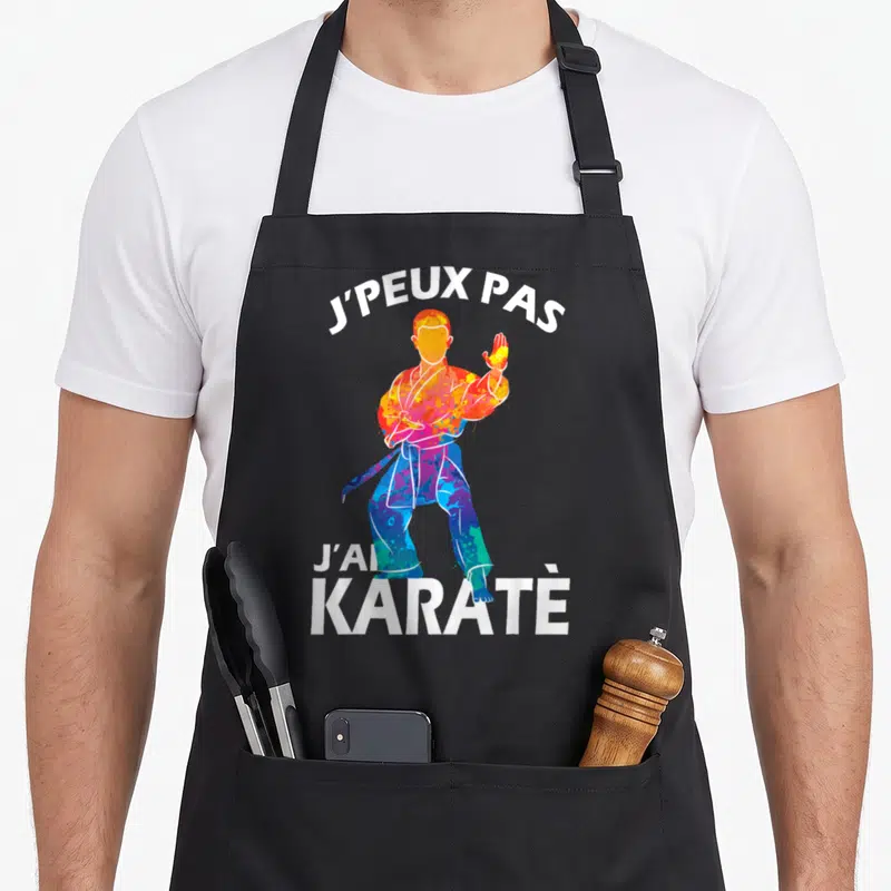 Tablier de cuisine noir avec une silhouette de karatéka multicolore et le texte j'peux pas j'ai karaté en blanc.