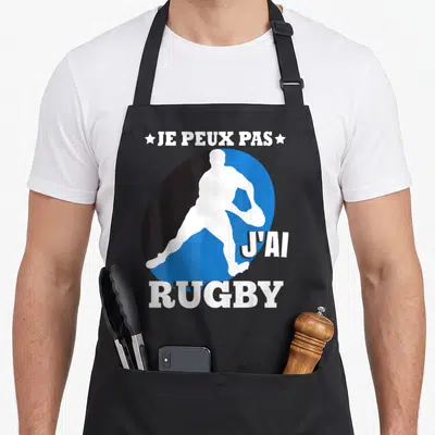 Tablier de cuisine noir avec silhouette blanche de joueur de rugby sur fond noir et bleu.