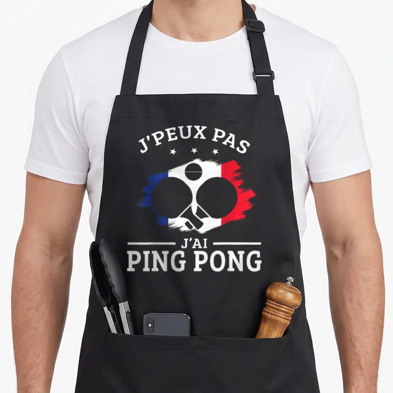 Tablier de cuisine noir avec inscription J'peux pas j'ai Ping Pong et deux paddles croisés sur fond tricolore.