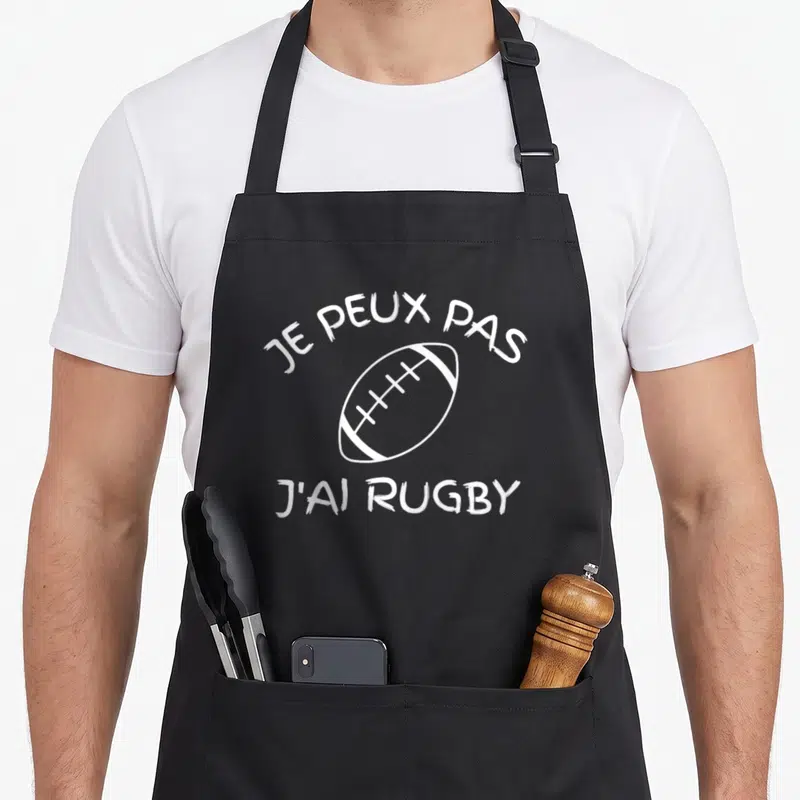 Tablier de cuisine noir avec inscription je peux pas j'ai rugby et dessin de ballon blanc.
