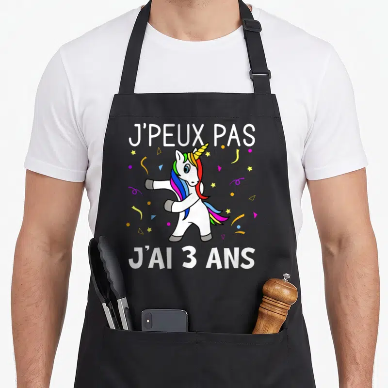 Tablier de cuisine noir avec une licone blanche aux cheveux multicolores effectuant un mouvement de danse sous des confettis.