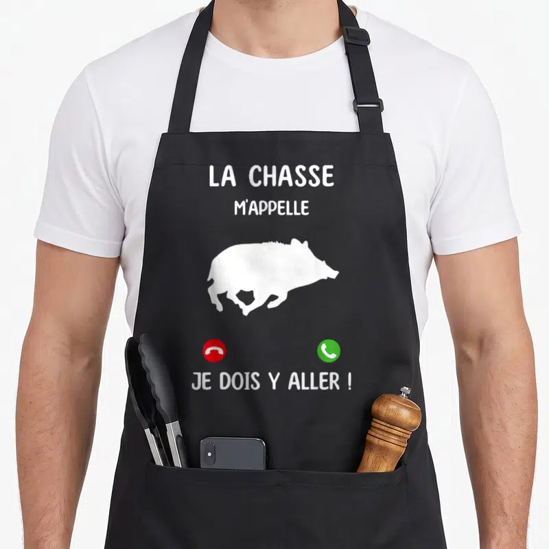 Tablier de cuisine noir avec silhouette de sanglier blanc et texte La chasse m'appelle Je dois y aller.